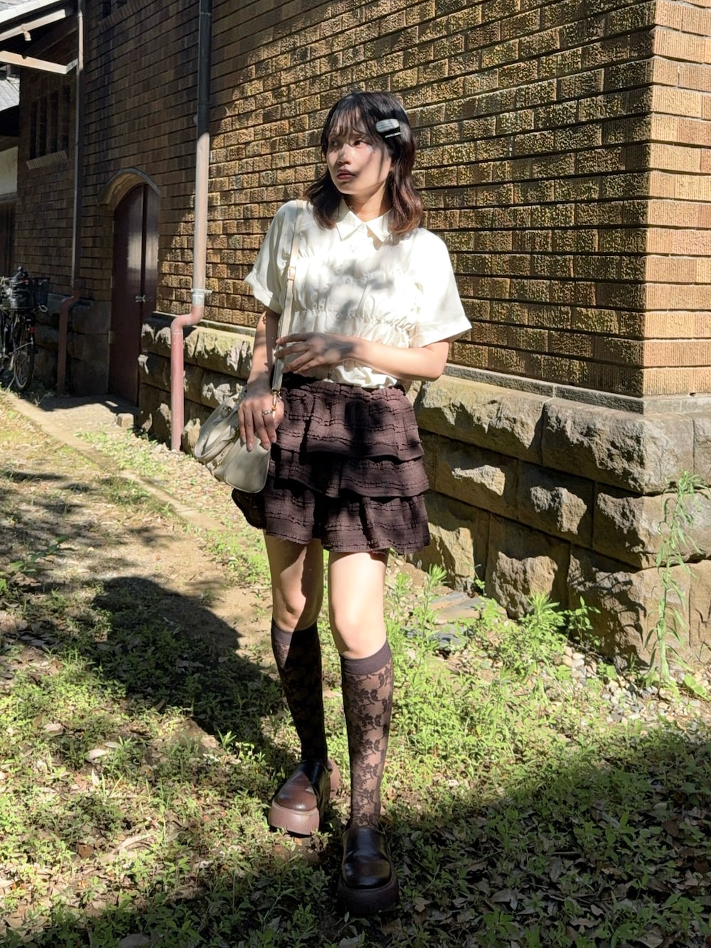 ブラウン系のスカート、ブラック系のサンダル、ベージュ系のシャツ/ブラウスを着用したレディースの夏コーディネートの1枚目の写真
