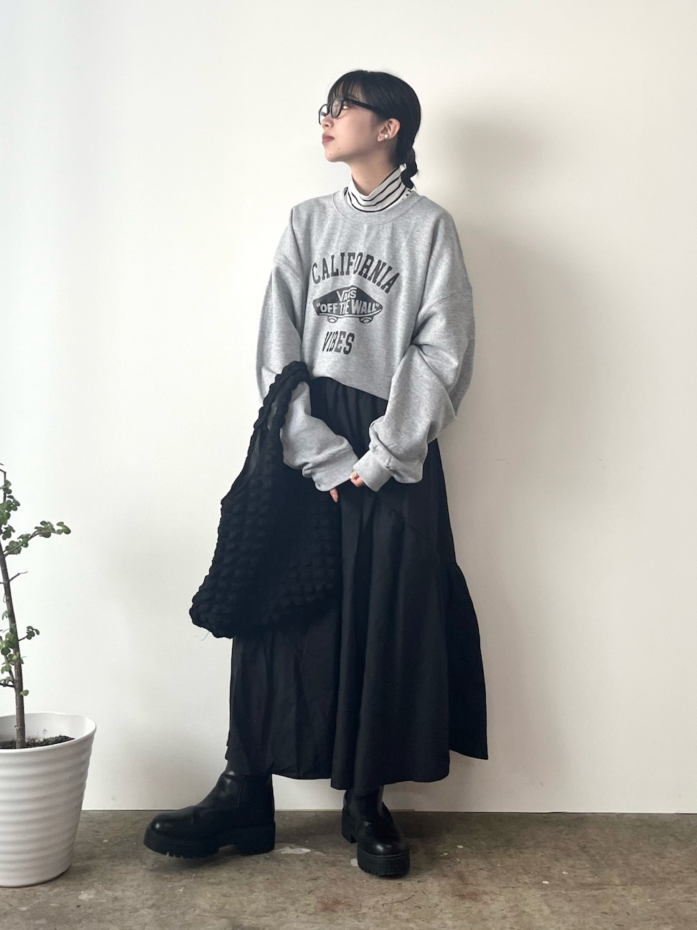 グレー系のスウェット、ブラック系のスカート、ブラック系のブーツを着用したレディースの秋コーディネートの1枚目の写真