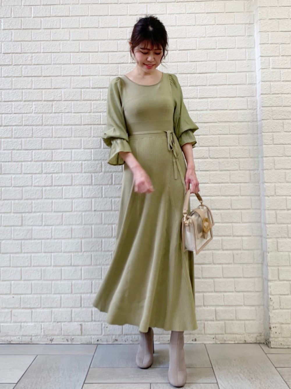 ホワイト系のトレンチコート、グリーン系のワンピースを着用したレディースの冬コーディネートの1枚目の写真