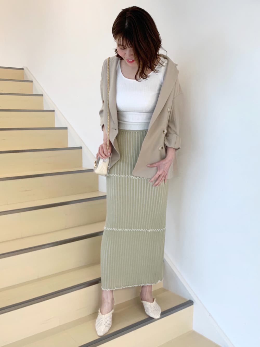 ベージュ系のパンプス、イエロー系のスカート、ホワイト系のニット/セーターを着用したレディースの春コーディネートの1枚目の写真