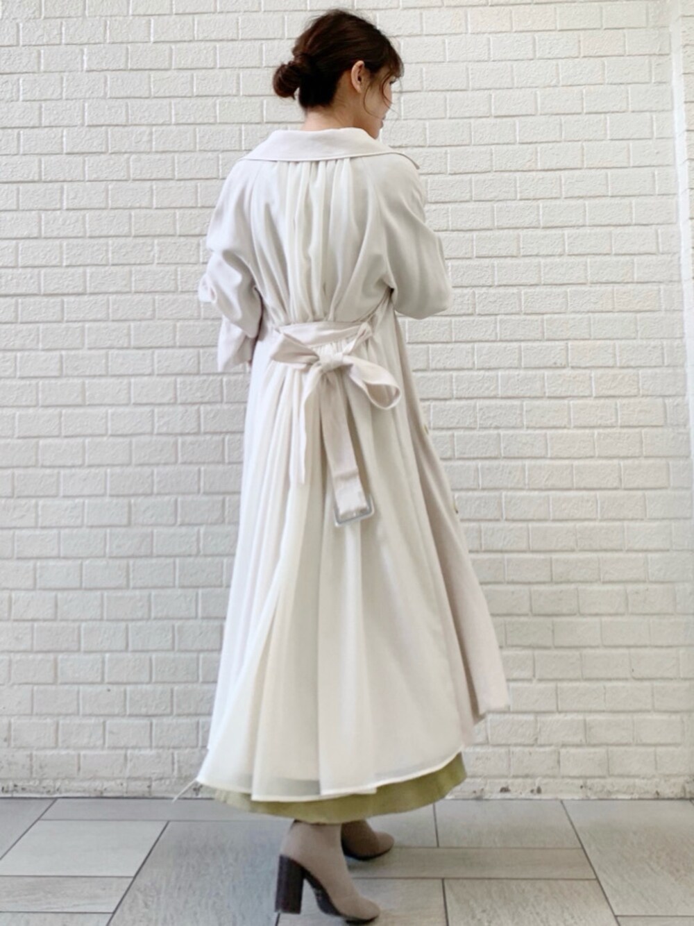 ホワイト系のトレンチコート、グリーン系のワンピースを着用したレディースの冬コーディネートの1枚目の写真