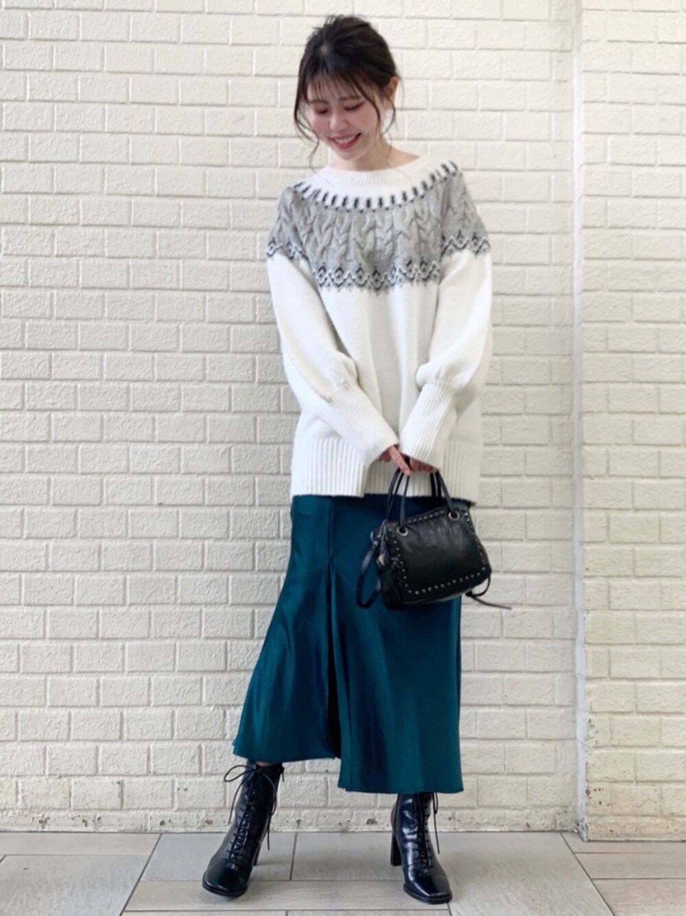 グリーン系のスカート、ホワイト系のニット/セーターを着用したレディースの冬コーディネートの1枚目の写真