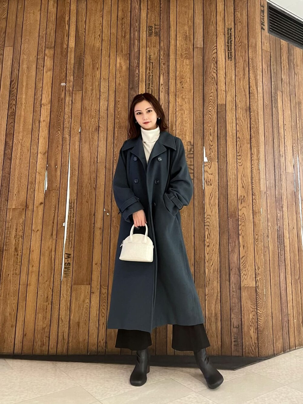 ブラック系のブーツ、ブラック系のその他パンツ、ホワイト系のハンドバッグを着用したレディースの秋コーディネートの1枚目の写真