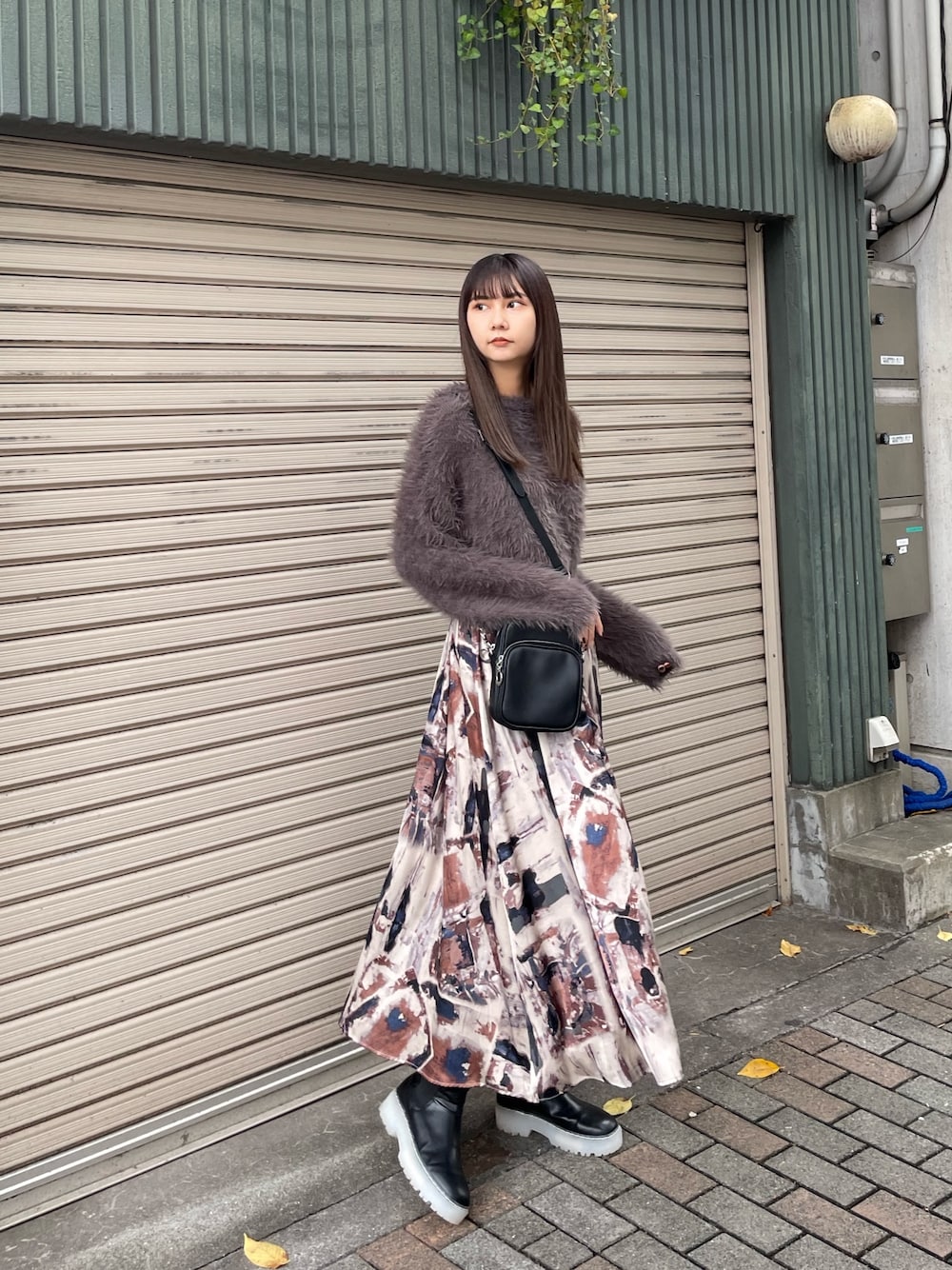 グレー系のニット/セーター、ブラック系のブーツ、ブルー系のスカートを着用したレディースの秋コーディネートの1枚目の写真