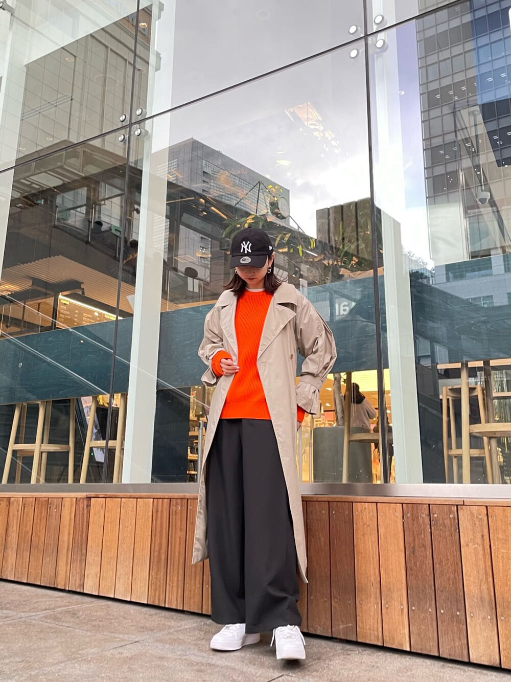 ベージュ系のトレンチコート、オレンジ系のニット/セーター、ブラック系のスラックスを着用したレディースの冬コーディネートの1枚目の写真