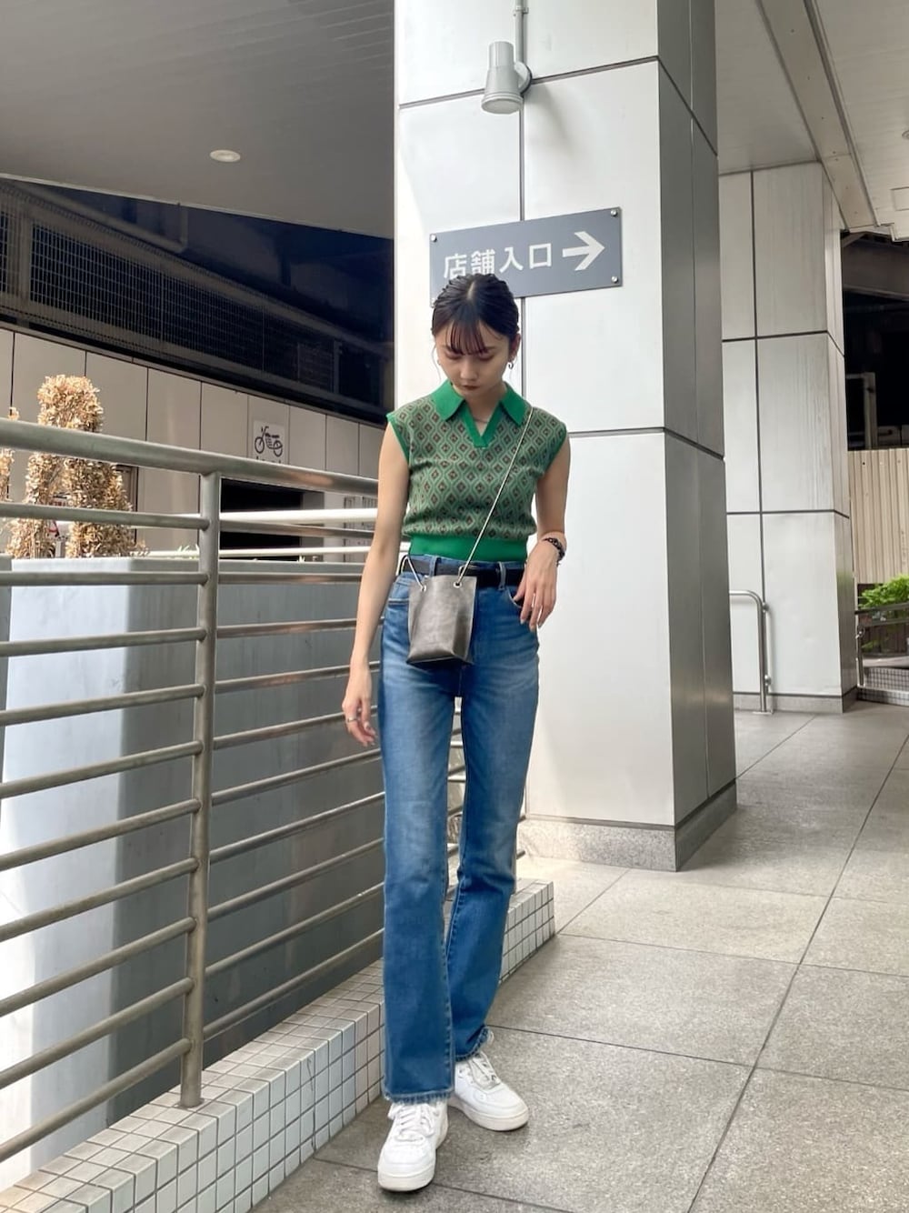 ブルー系のデニムパンツ、ブラック系のショルダーバッグ、グリーン系のニット/セーターを着用したレディースの夏コーディネートの1枚目の写真