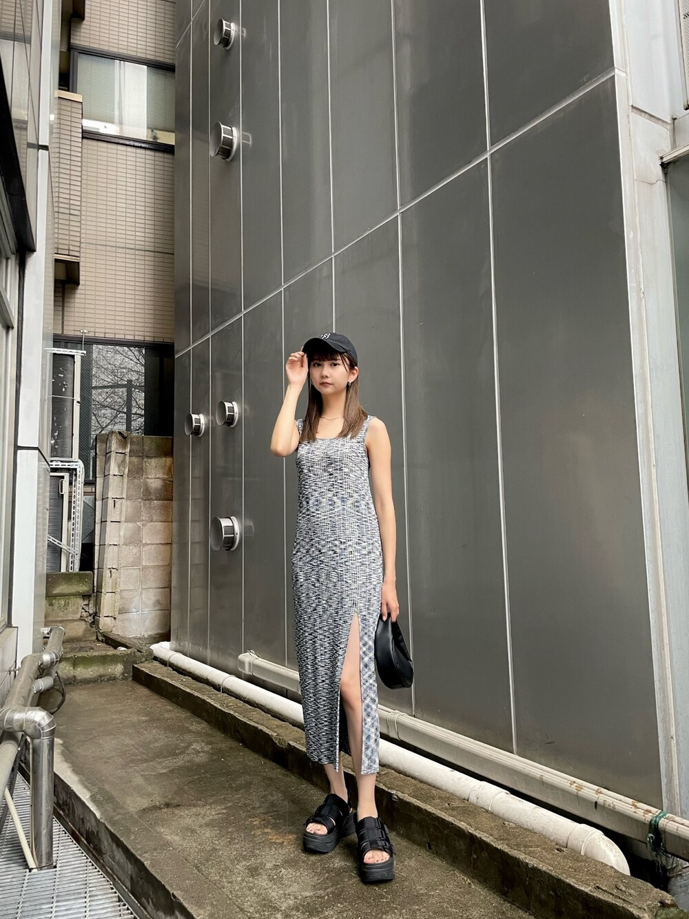 ブルー系のワンピース、ブラック系のサンダル、ブラック系のハンドバッグを着用したレディースの春コーディネートの1枚目の写真