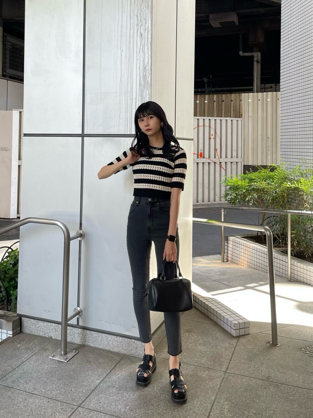 ブラック系のニット/セーター、グレー系のデニムパンツ、ブラック系のサンダルを着用したレディースの春コーディネートの1枚目の写真