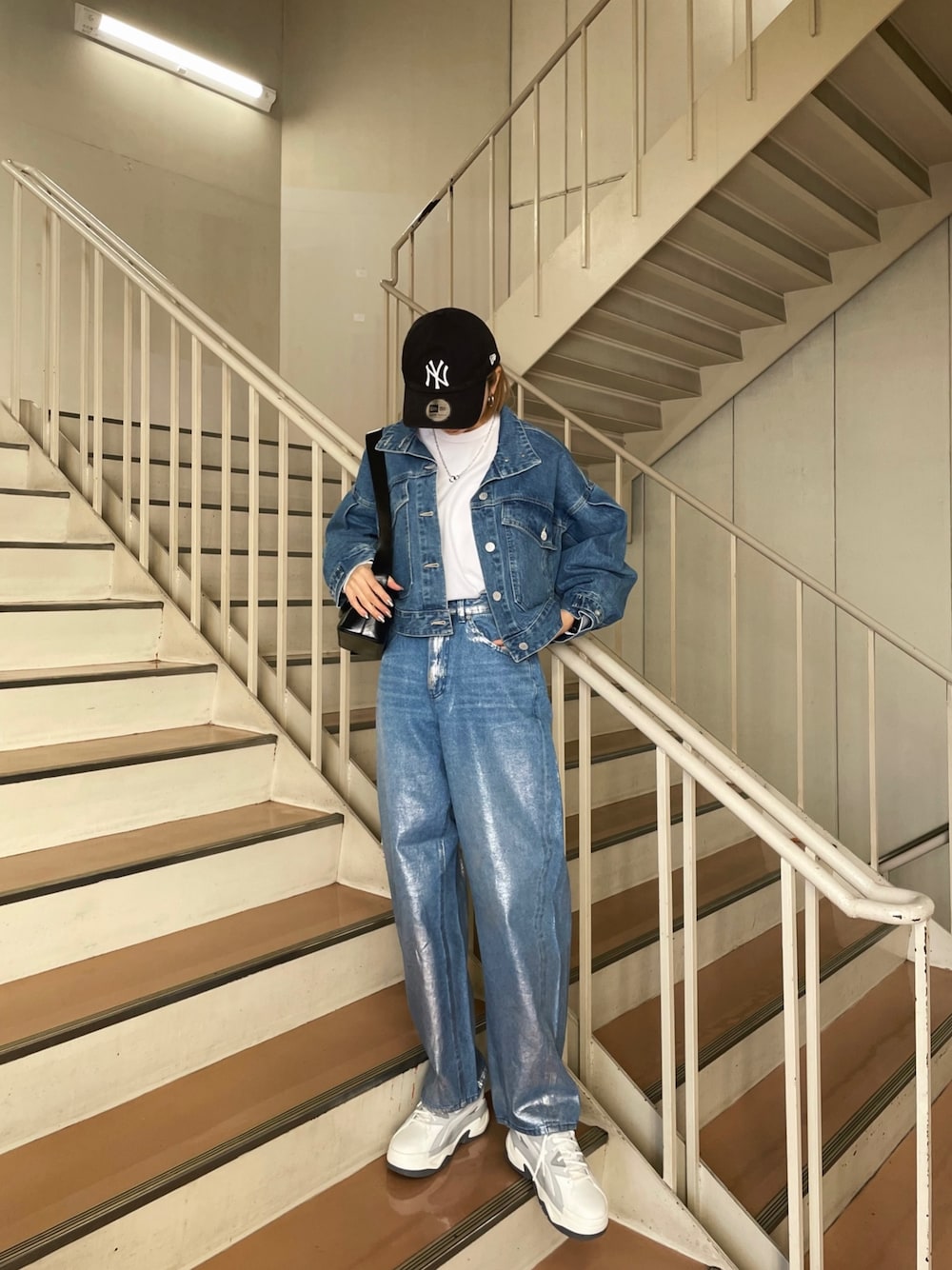 グレー系のスニーカー、ブルー系のデニムパンツ、ブルー系のデニムジャケットを着用したレディースの冬コーディネートの1枚目の写真