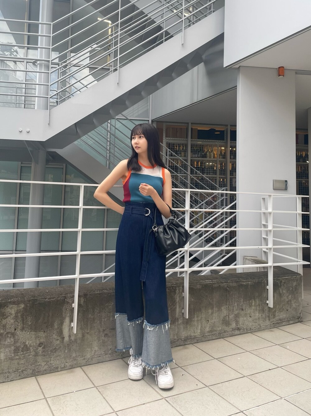 ブルー系のニット/セーター、ブラック系のハンドバッグ、ブルー系のデニムパンツを着用したレディースの春コーディネートの1枚目の写真