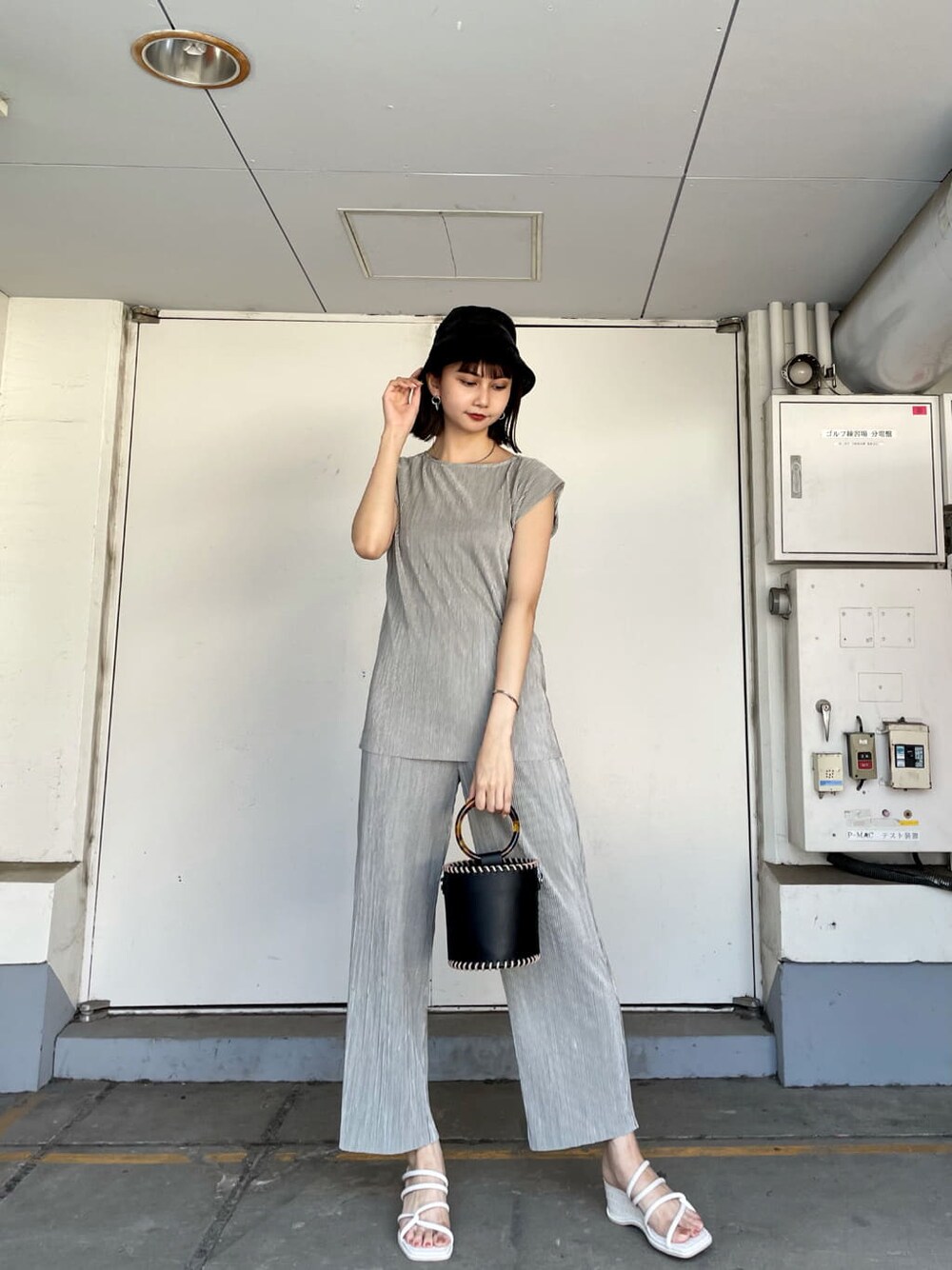 グレー系のスウェットパンツ、ブラック系のハンドバッグ、ホワイト系のサンダルを着用したレディースの夏コーディネートの1枚目の写真