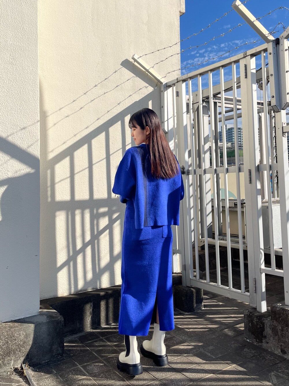 ブルー系のニット/セーター、ブルー系のスカート、ホワイト系のブーツを着用したレディースの冬コーディネートの1枚目の写真