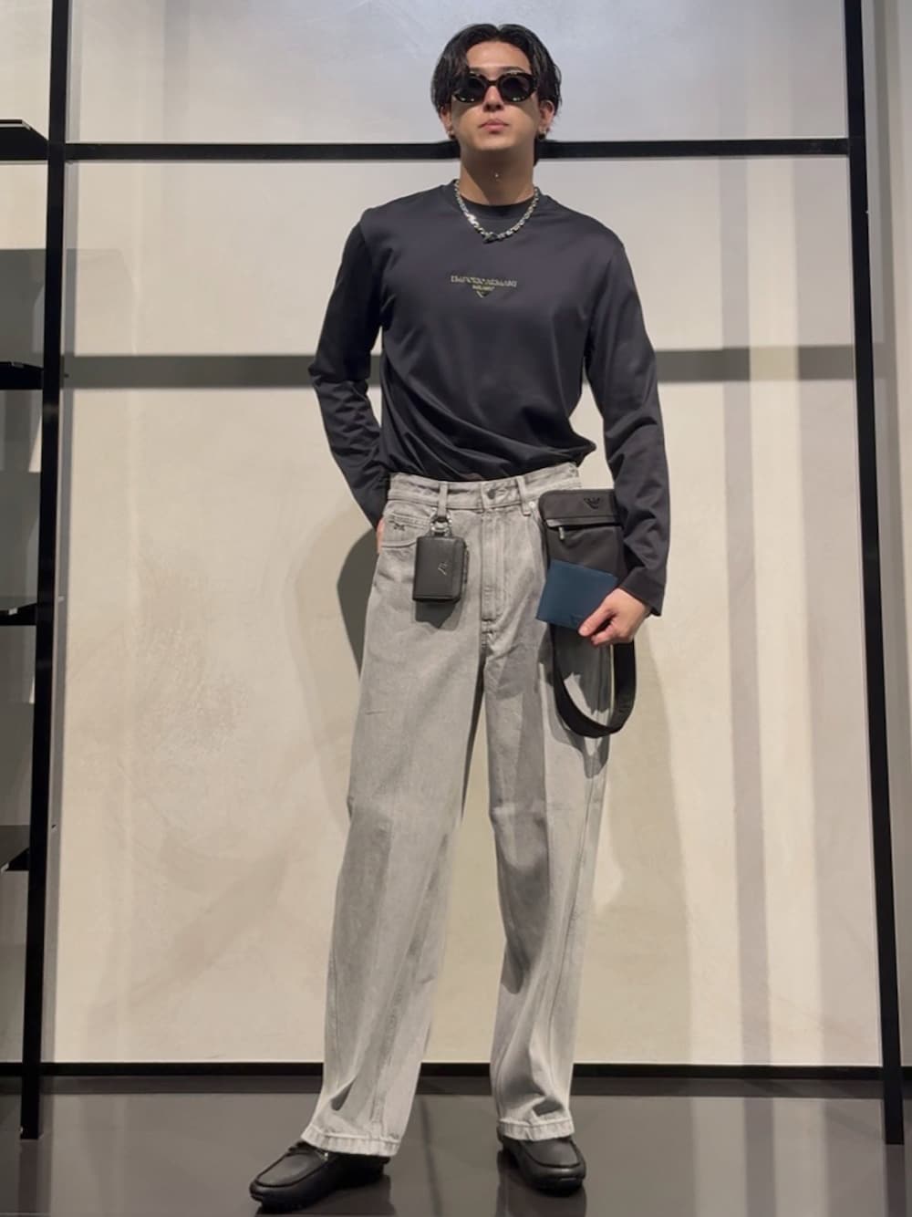 ブルー系のTシャツ/カットソー、グレー系のデニムパンツ、ブラック系のショルダーバッグを着用したメンズの秋コーディネートの1枚目の写真