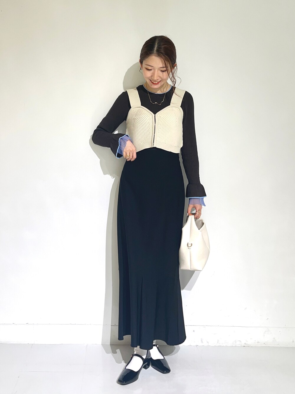 ブラック系のパンプス、ブラック系のスカート、グレー系のニット/セーターを着用したレディースの冬コーディネートの1枚目の写真