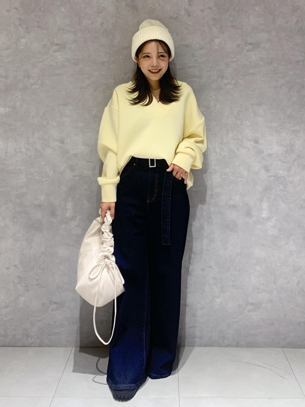 ブルー系のデニムパンツ、ホワイト系のブーツ、ホワイト系のショルダーバッグを着用したレディースの秋コーディネートの1枚目の写真