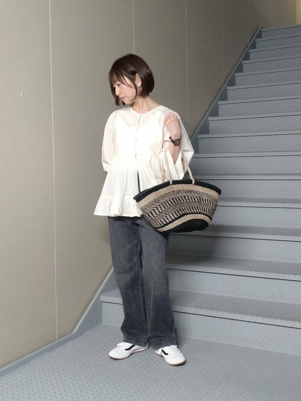 ブラック系のデニムパンツ、ベージュ系のかごバッグ、ホワイト系のシャツ/ブラウスを着用したレディースの春コーディネートの1枚目の写真