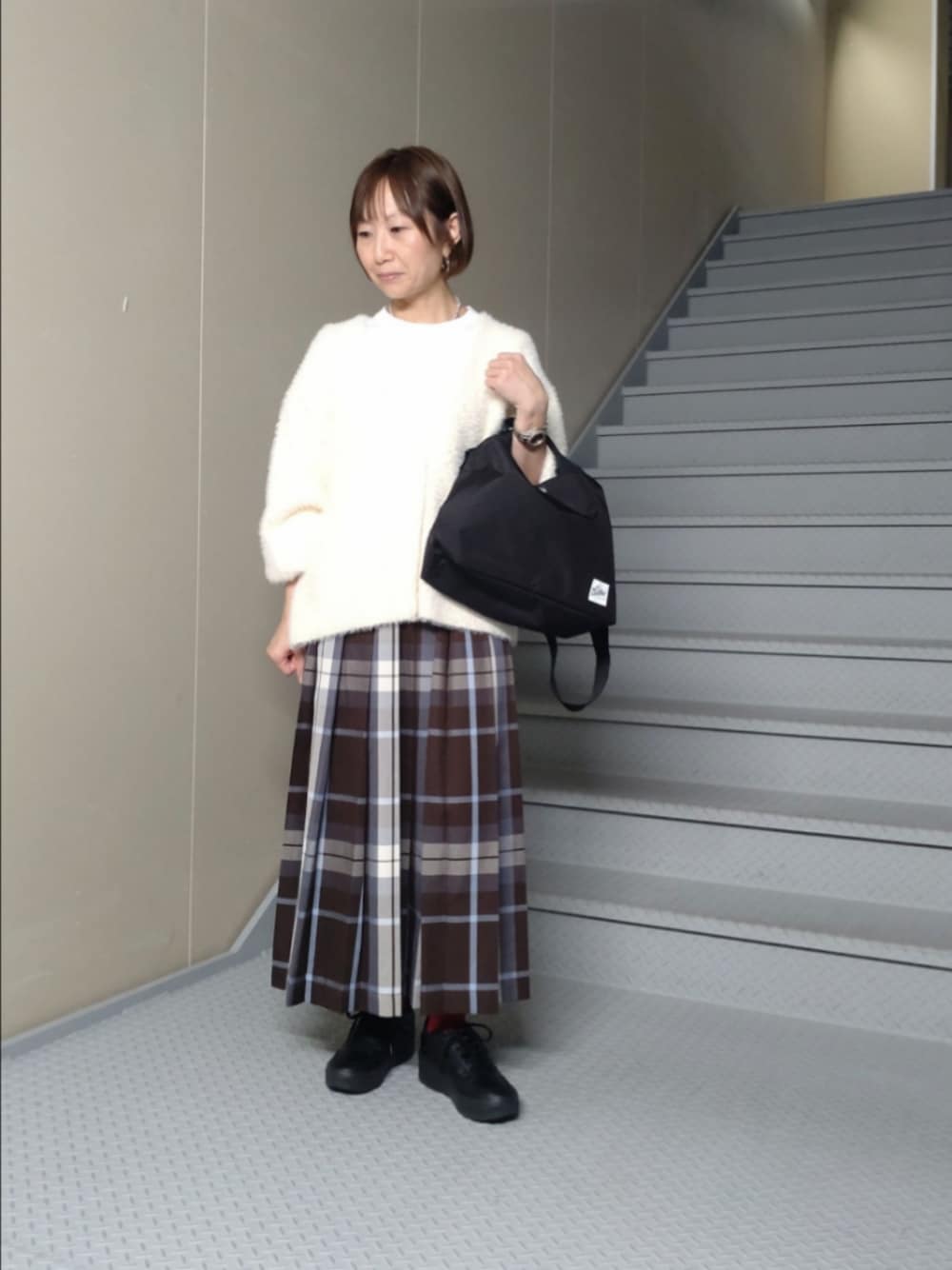ホワイト系のカーディガン/ボレロ、ブラウン系のスカート、ブラック系のショルダーバッグを着用したレディースの秋コーディネートの1枚目の写真