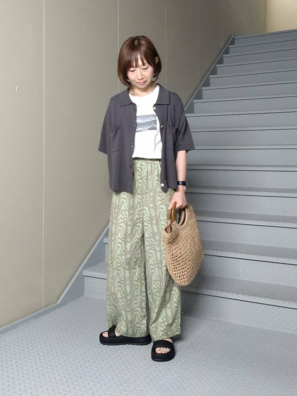 ベージュ系のトートバッグ、グレー系のニット/セーター、ホワイト系のTシャツ/カットソーを着用したレディースの春コーディネートの1枚目の写真