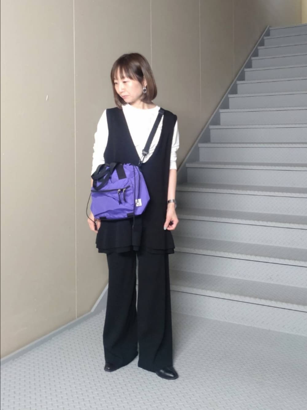 ブルー系のトートバッグ、ホワイト系のTシャツ/カットソー、ブラック系のニット/セーターを着用したレディースの冬コーディネートの1枚目の写真