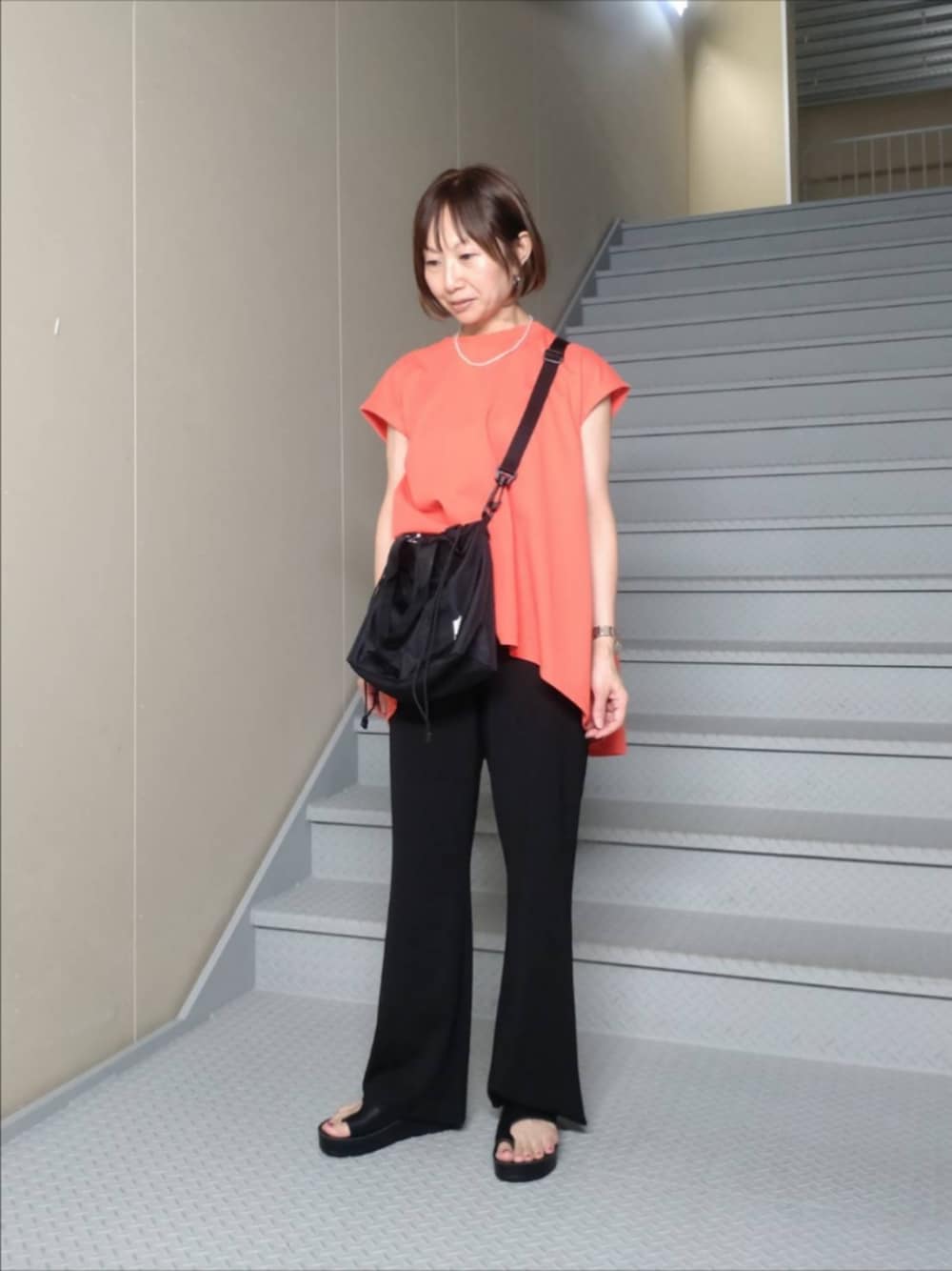 レッド系のTシャツ/カットソー、ブラック系のその他パンツ、ブラック系のトートバッグを着用したレディースの夏コーディネートの1枚目の写真
