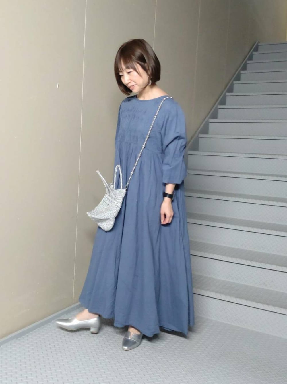 シルバー系のパンプス、シルバー系のショルダーバッグ、ブルー系のワンピースを着用したレディースの春コーディネートの1枚目の写真