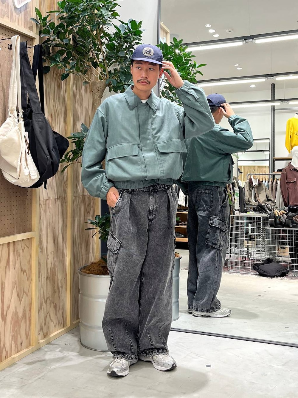 グレー系のデニムパンツ、ホワイト系のTシャツ/カットソー、グリーン系のブルゾンを着用したメンズの秋コーディネートの1枚目の写真