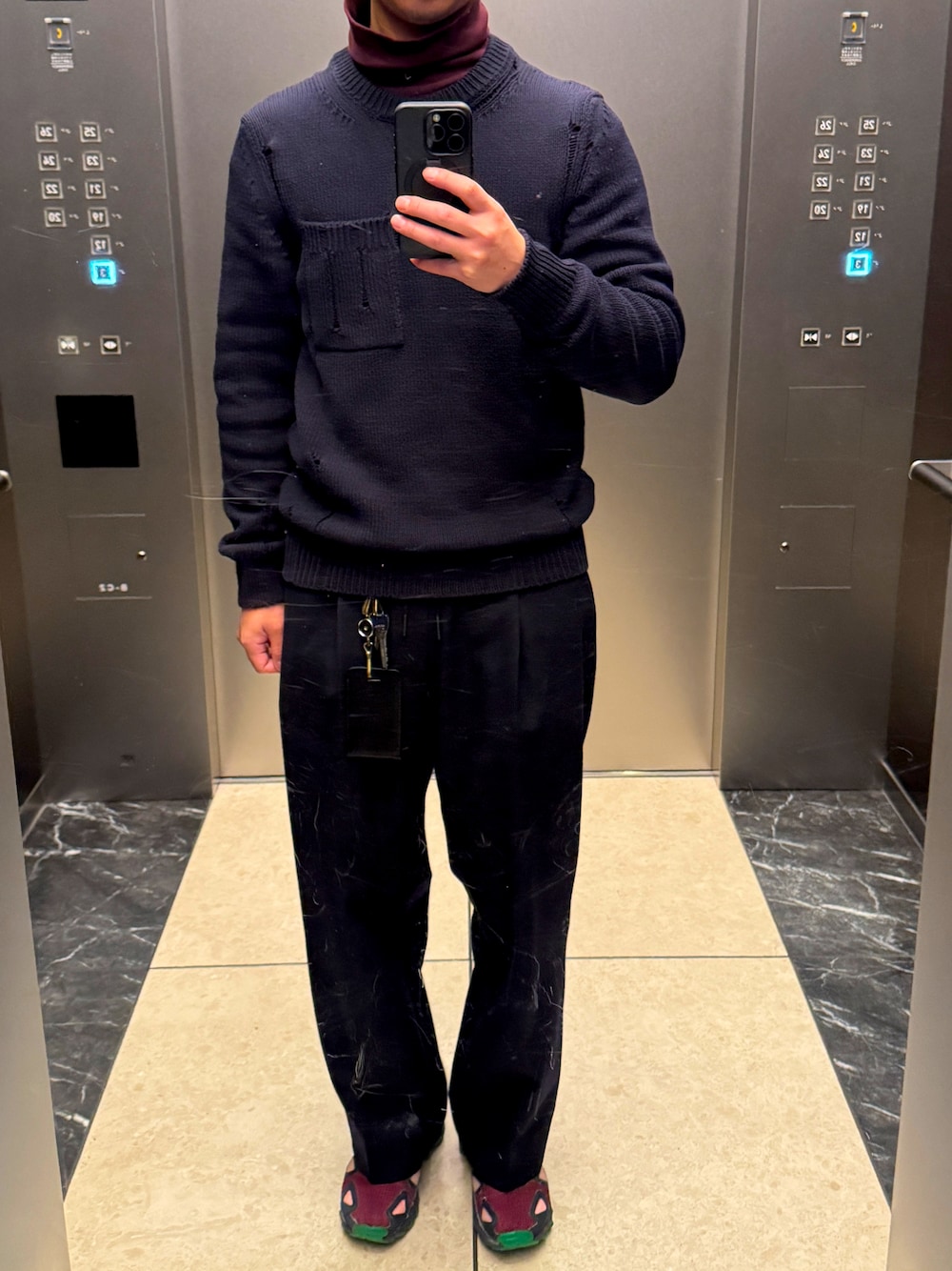 ブラック系のスラックス、レッド系のスニーカー、ブラック系のニット/セーターを着用したメンズの冬コーディネートの1枚目の写真