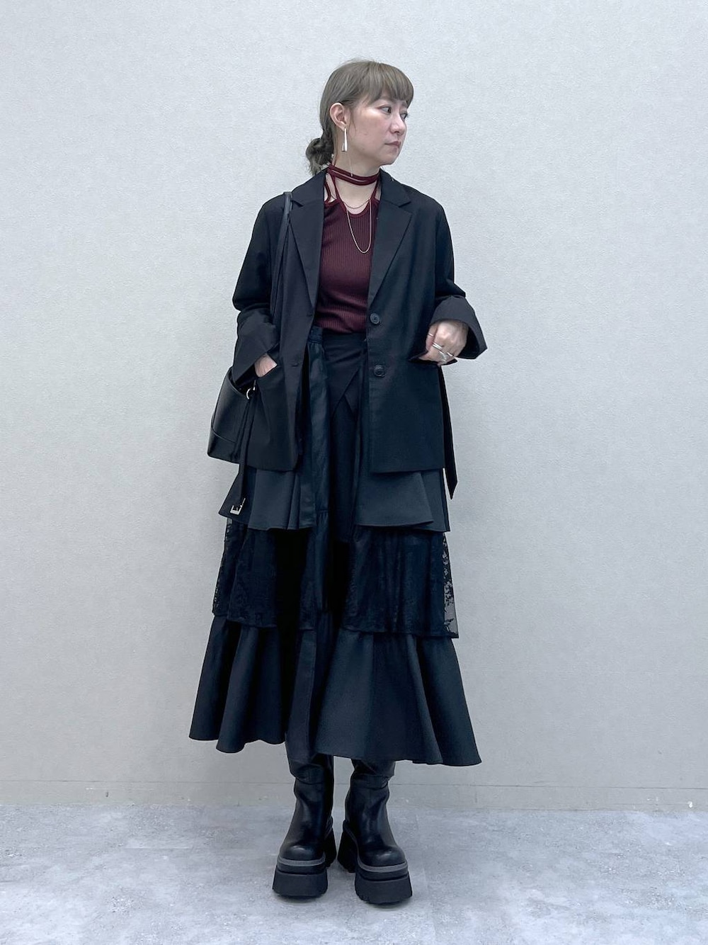 ブラック系のショルダーバッグ、その他のスカート、ブラック系のブーツを着用したレディースの秋コーディネートの1枚目の写真