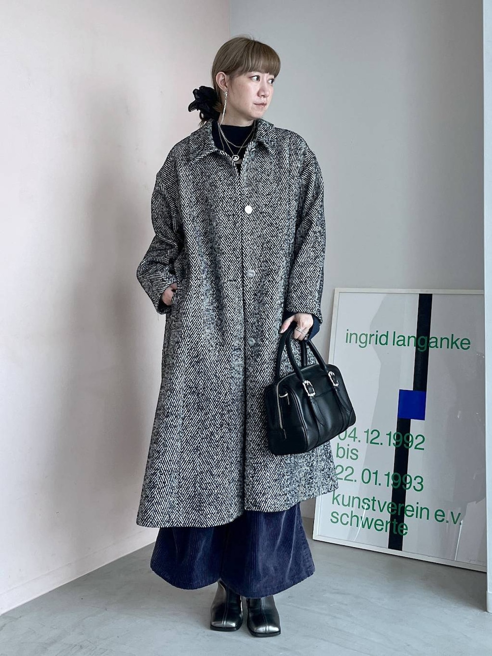 グレー系のステンカラーコート、ブラック系のボストンバッグ、シルバー系のブーツを着用したレディースの秋コーディネートの1枚目の写真