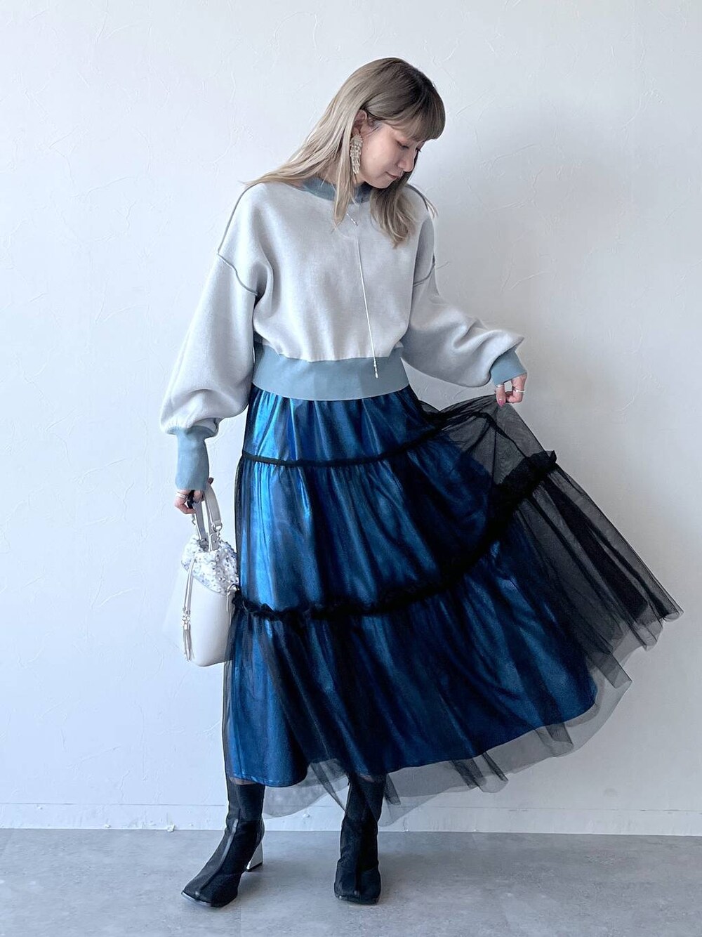 ブルー系のカーディガン/ボレロ、ブルー系のスカート、ホワイト系のショルダーバッグを着用したレディースの冬コーディネートの1枚目の写真