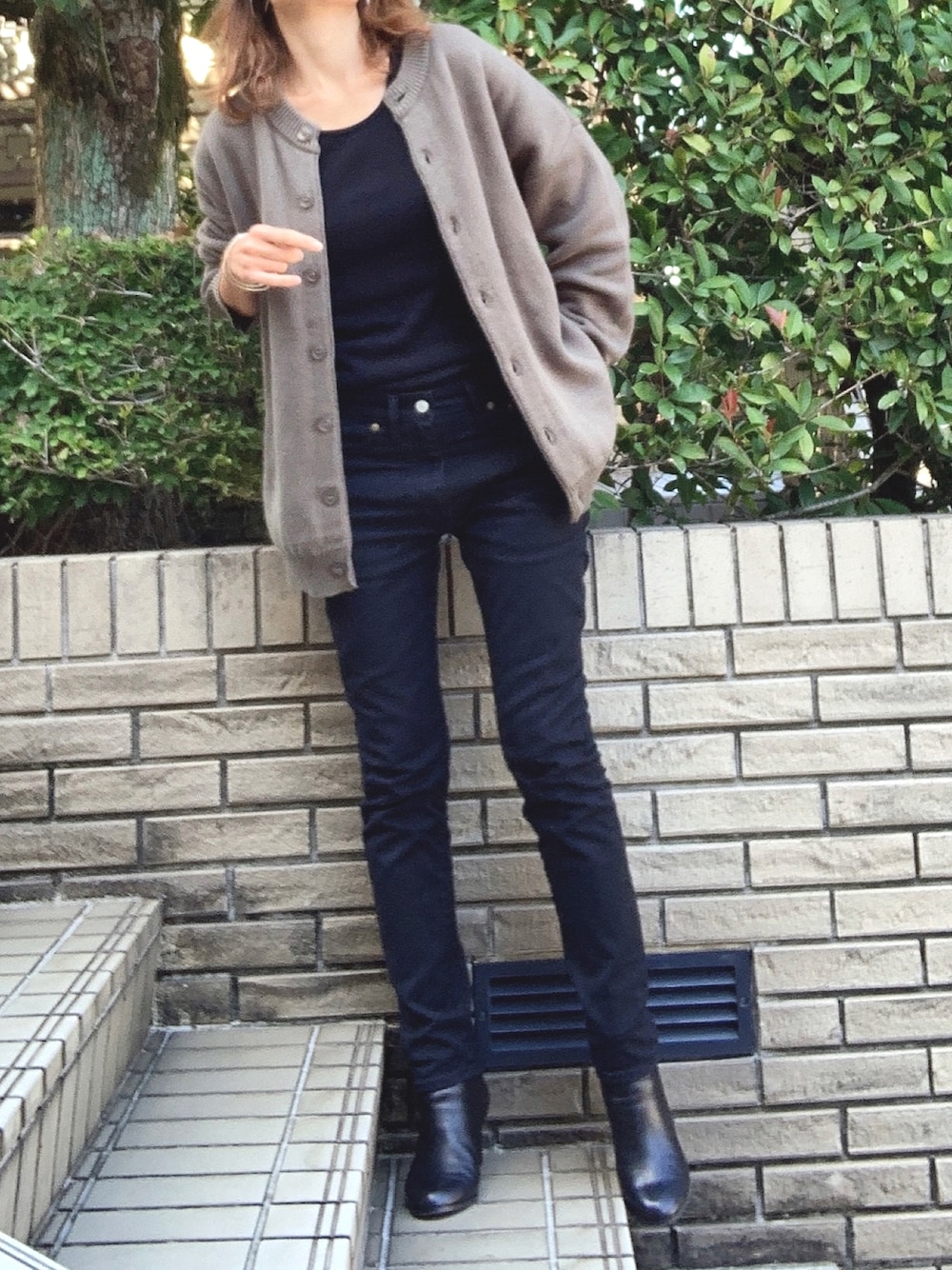 ブラック系のタンクトップ、ブラック系のデニムパンツ、グリーン系のカーディガン/ボレロを着用したレディースの秋コーディネートの1枚目の写真