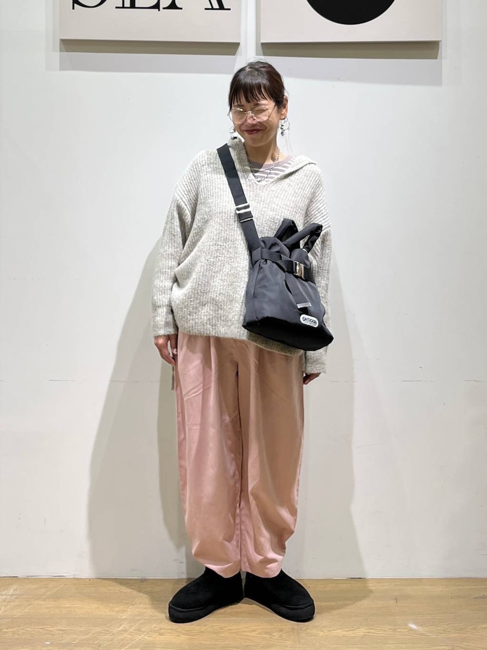 ブラック系のトートバッグ、ベージュ系のTシャツ/カットソー、ブラック系のブーツを着用したレディースの秋コーディネートの1枚目の写真