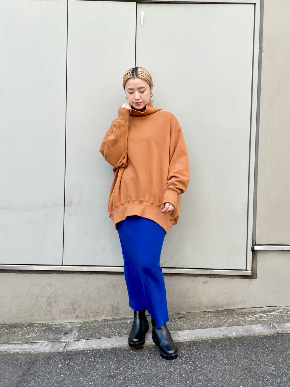 イエロー系のスウェット、ブルー系のスカート、ブラック系のブーツを着用したレディースの秋コーディネートの1枚目の写真