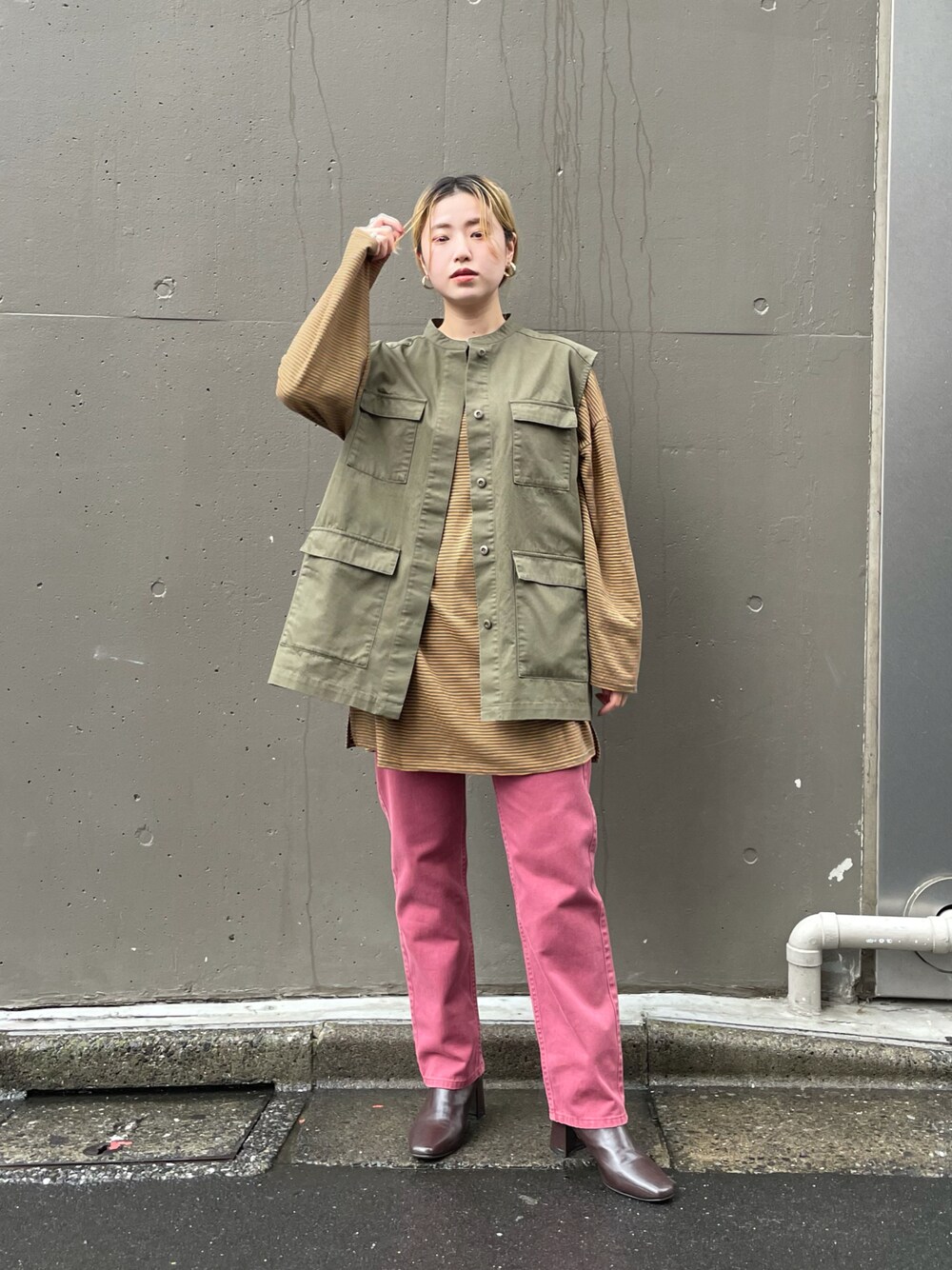 ピンク系のデニムパンツ、グリーン系のベスト、グリーン系のTシャツ/カットソーを着用したレディースの秋コーディネートの1枚目の写真