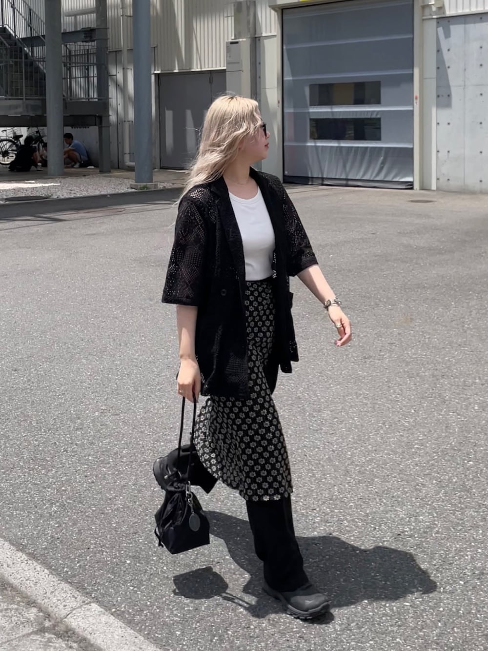 ブラック系のテーラードジャケット、ブラック系のスカート、ブラック系のショルダーバッグを着用したレディースの夏コーディネートの1枚目の写真