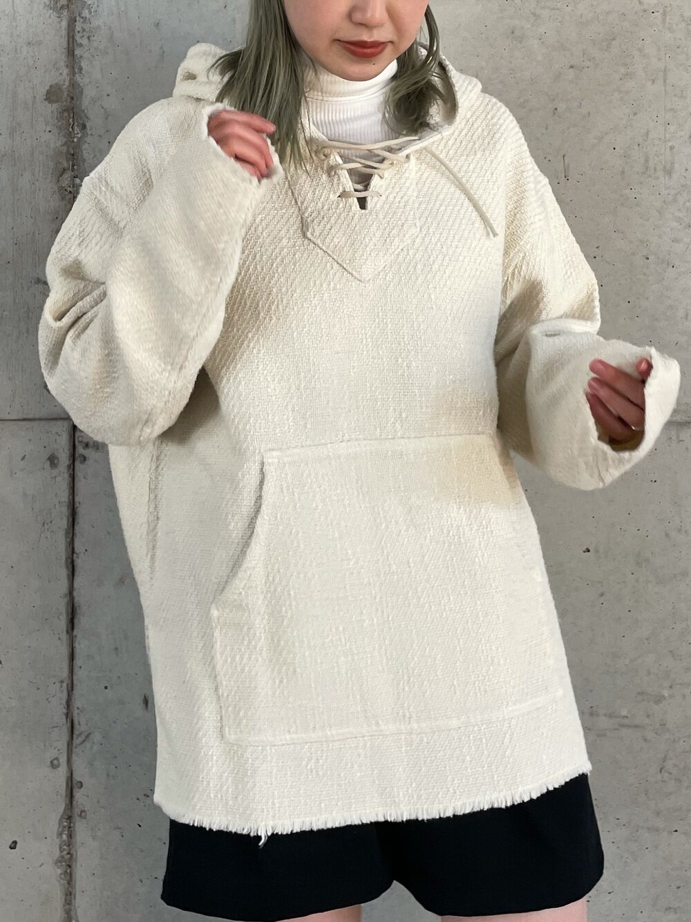 ホワイト系のパーカー、ブラック系のショルダーバッグ、ブラック系のブーツを着用したレディースの冬コーディネートの2枚目の写真