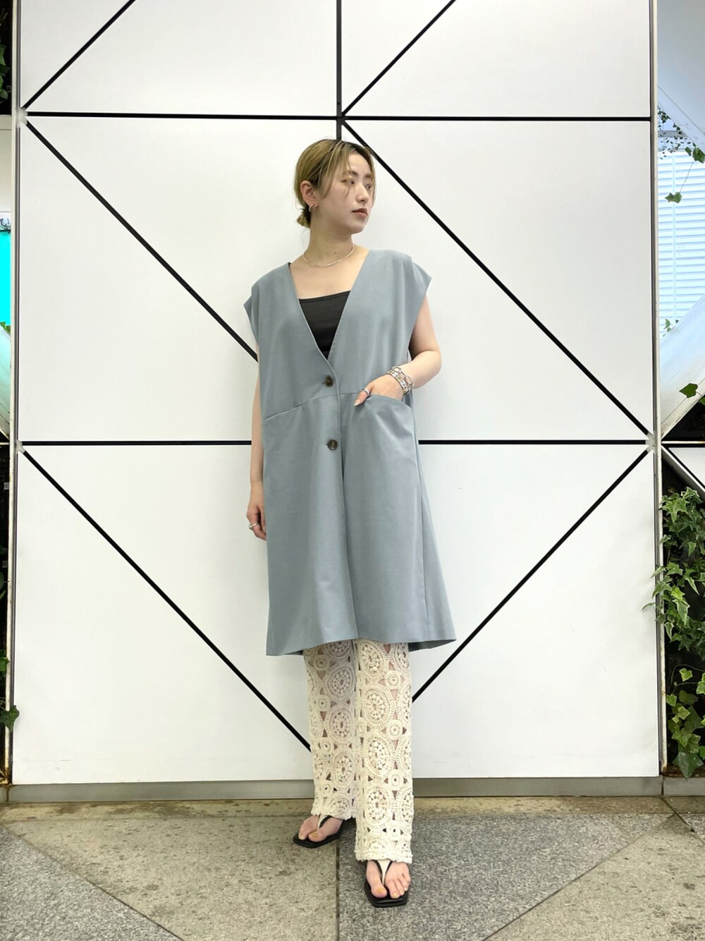 グレー系のタンクトップ、ブルー系のベスト、ホワイト系のスラックスを着用したレディースの夏コーディネートの1枚目の写真
