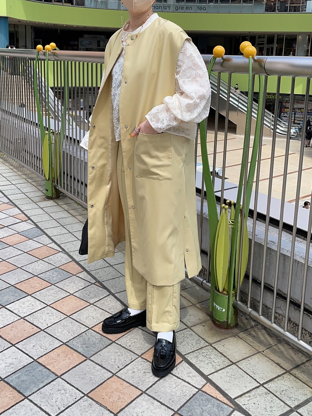 イエロー系のベスト、ホワイト系のシャツ/ブラウス、イエロー系のスラックスを着用したレディースの春コーディネートの1枚目の写真