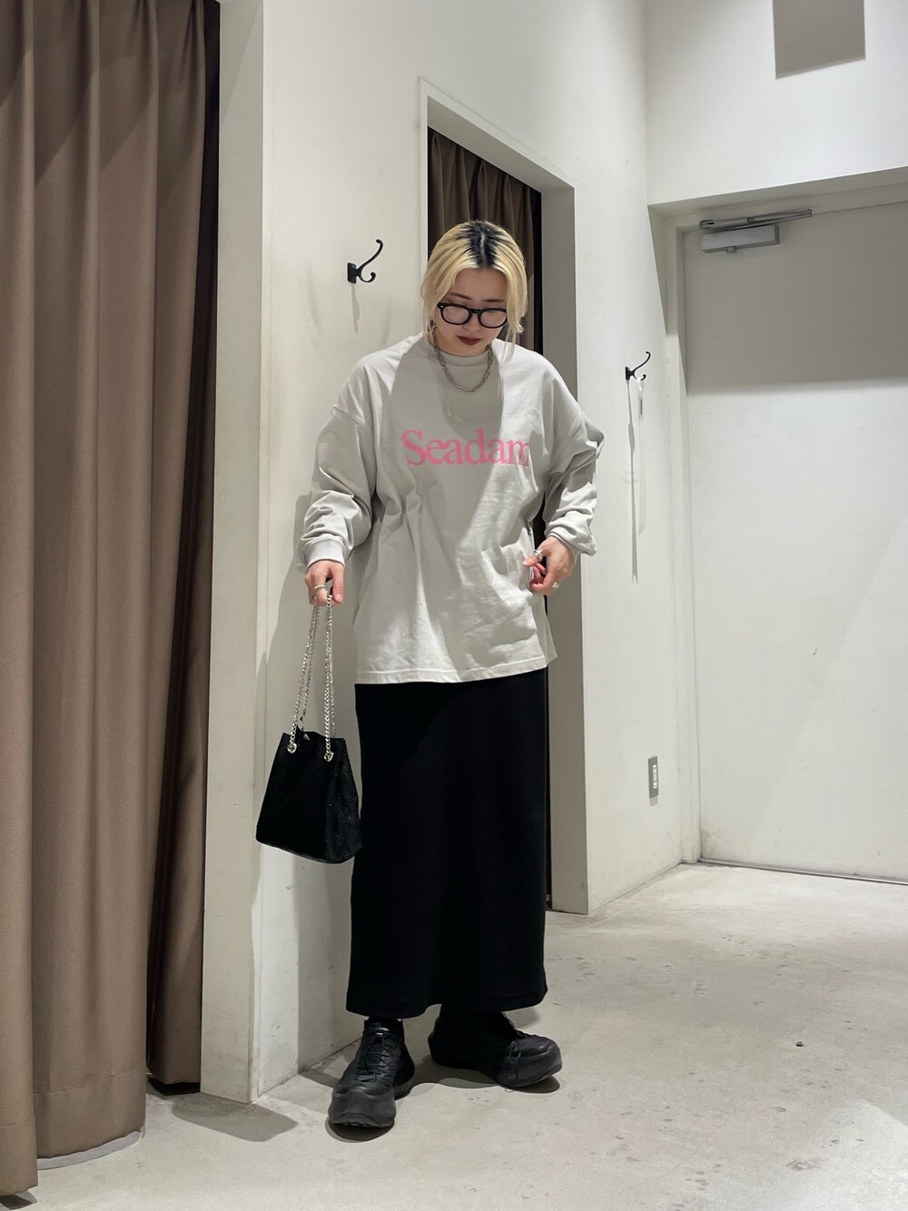 グレー系のTシャツ/カットソー、ブラック系のスカート、ブラック系のショルダーバッグを着用したレディースの春コーディネートの1枚目の写真