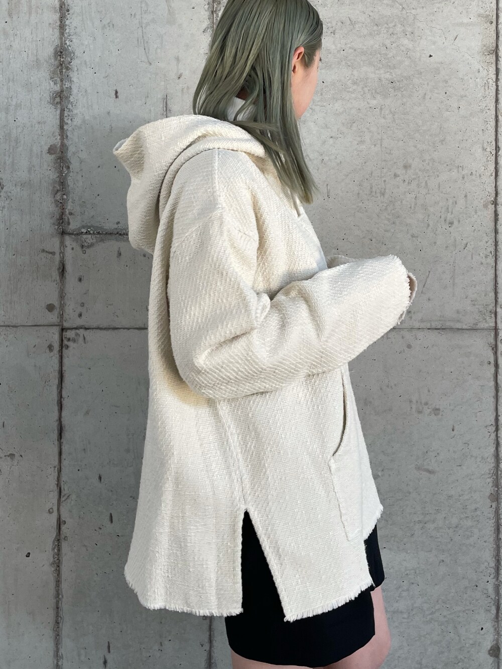 ホワイト系のパーカー、ブラック系のショルダーバッグ、ブラック系のブーツを着用したレディースの冬コーディネートの3枚目の写真