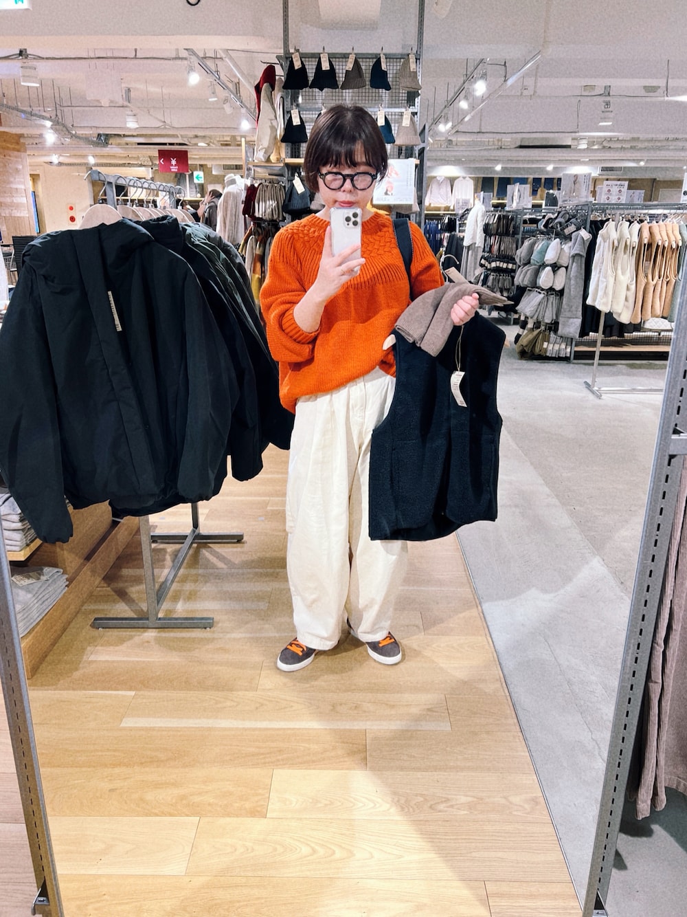 オレンジ系のニット/セーター、ベージュ系のその他パンツ、ブラウン系のスニーカーを着用したレディースの秋コーディネートの1枚目の写真