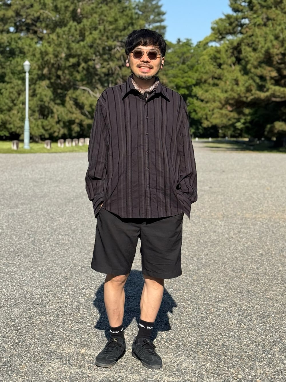 ブラック系のスニーカー、ブラック系のパンツを着用したメンズの夏コーディネートの1枚目の写真