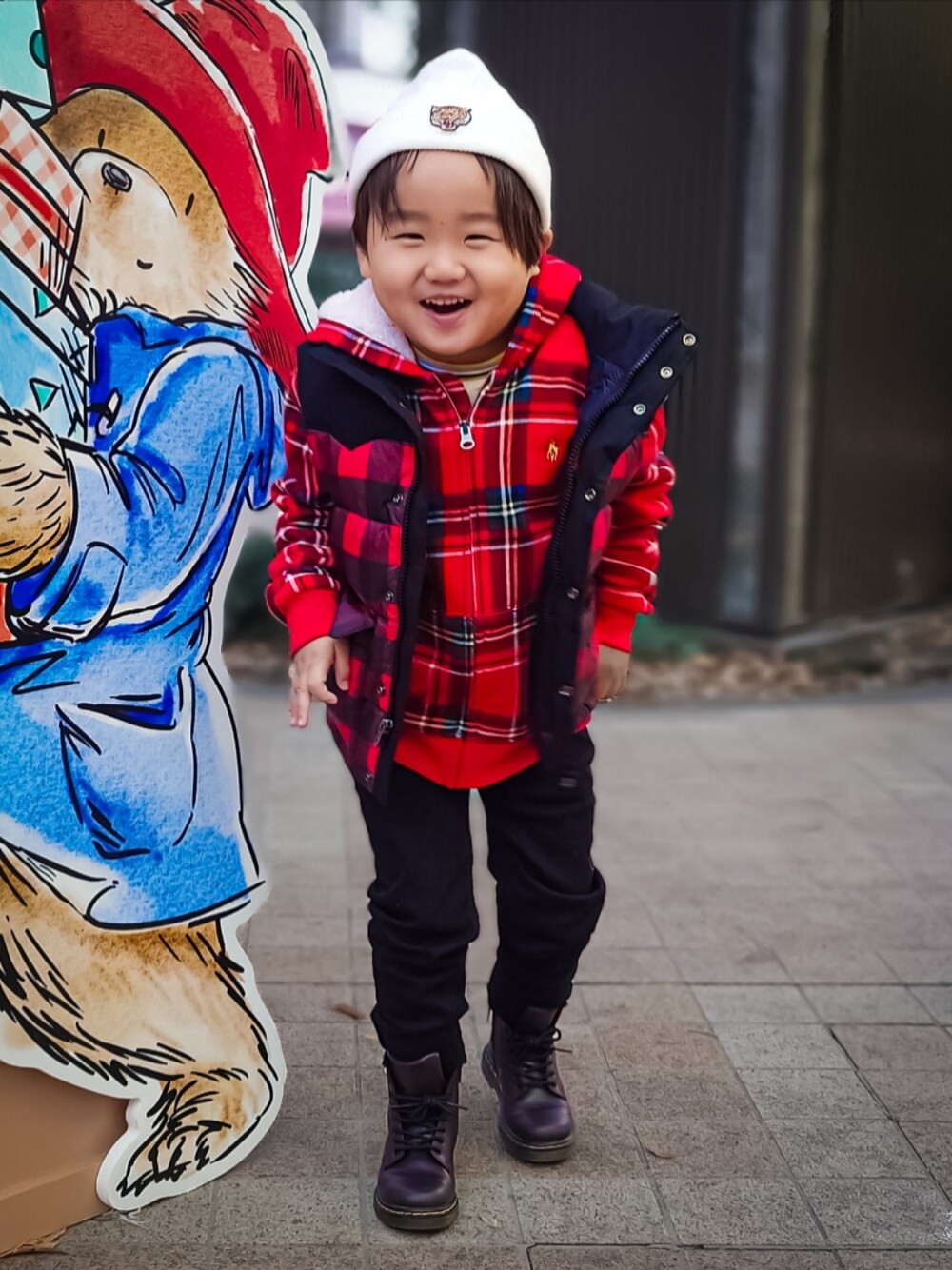 レッド系のダウンベスト、レッド系のパーカー、レッド系のブーツを着用したキッズの冬コーディネートの1枚目の写真