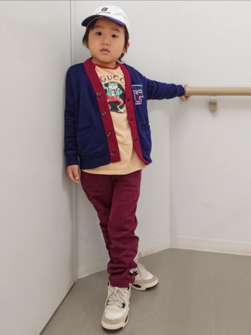 ブルー系のカーディガン/ボレロ、ベージュ系のTシャツ/カットソー、レッド系のパンツを着用したキッズの秋コーディネートの1枚目の写真