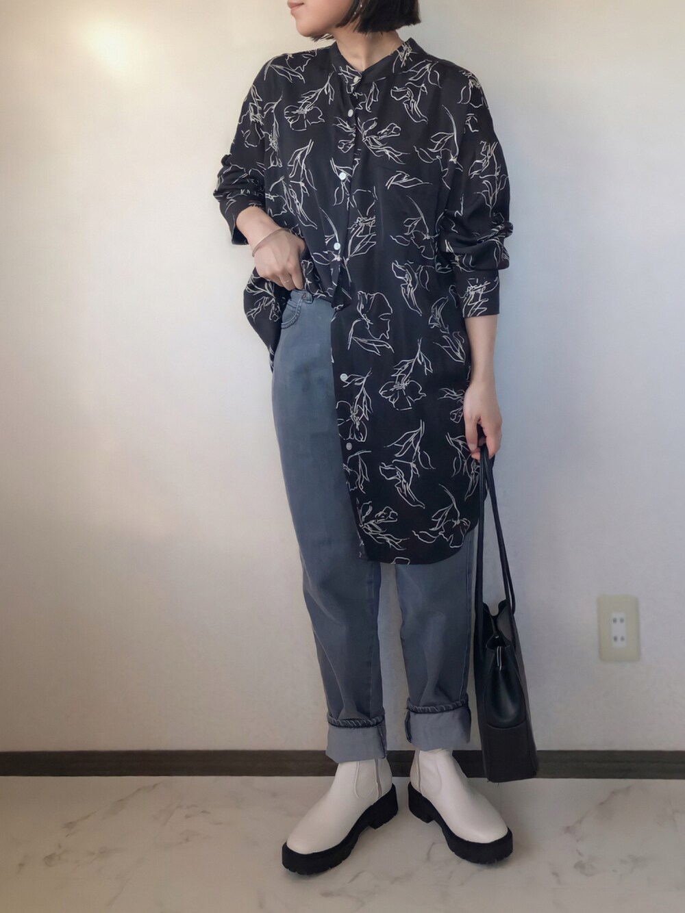 グレー系のデニムパンツ、ブラック系のショルダーバッグ、ホワイト系のブーツを着用したレディースの秋コーディネートの1枚目の写真