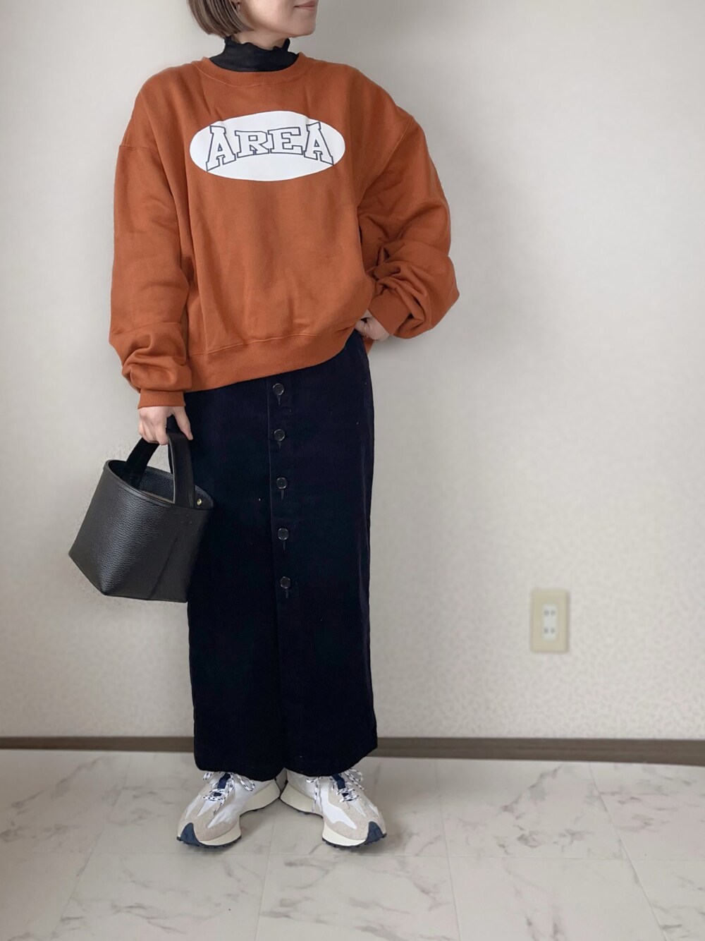 オレンジ系のスウェット、ブラック系のTシャツ/カットソー、ブルー系のスカートを着用したレディースの冬コーディネートの1枚目の写真