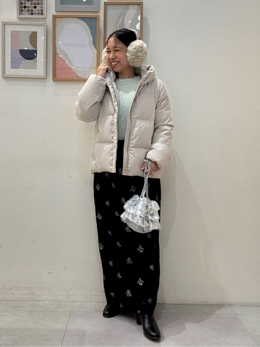 ベージュ系のダウンジャケット/コート、グリーン系のニット/セーター、ブラック系のスカートを着用したレディースの冬コーディネートの1枚目の写真