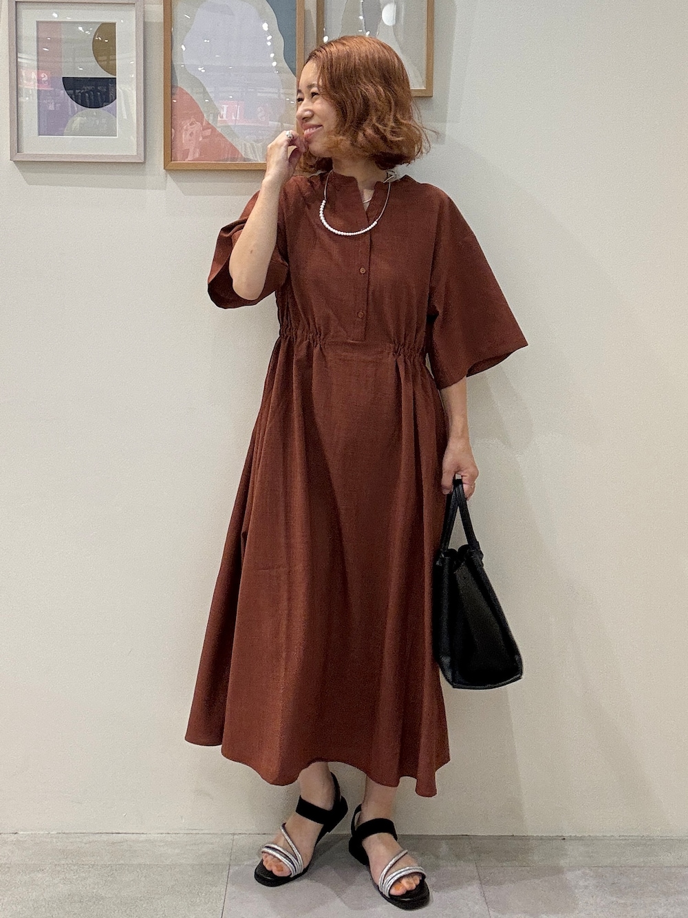 オレンジ系のワンピース、ブラック系のトートバッグ、ブラック系のサンダルを着用したレディースの夏コーディネートの1枚目の写真