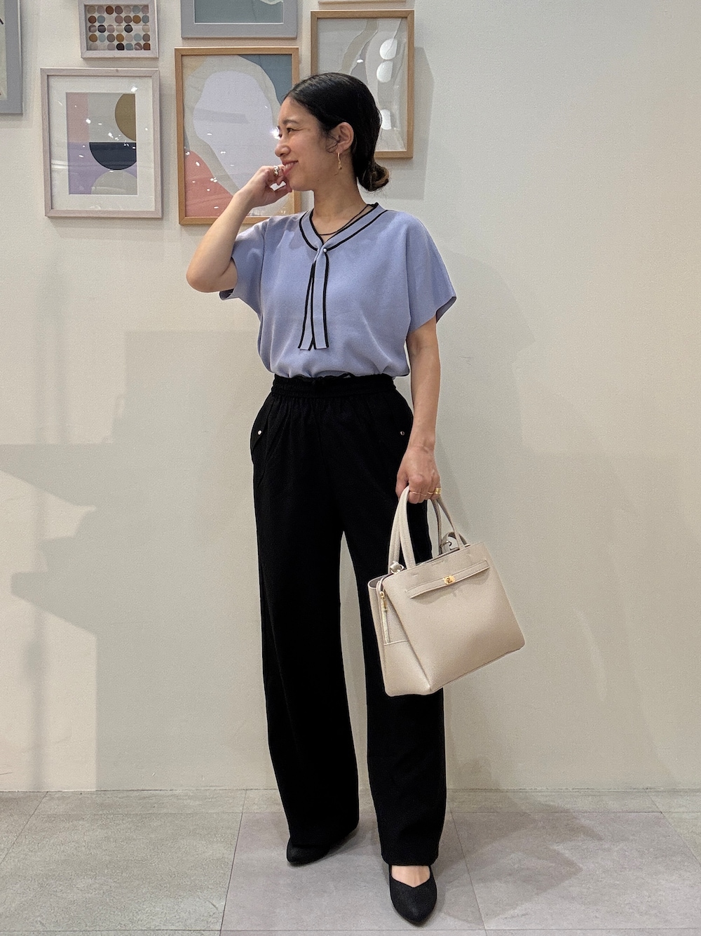 ブルー系のニット/セーター、ブラック系のその他パンツ、ベージュ系のトートバッグを着用したレディースの春コーディネートの1枚目の写真