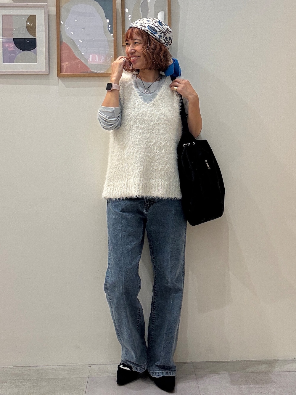 ホワイト系のベスト、ブルー系のデニムパンツ、ブラック系のショルダーバッグを着用したレディースの秋コーディネートの1枚目の写真
